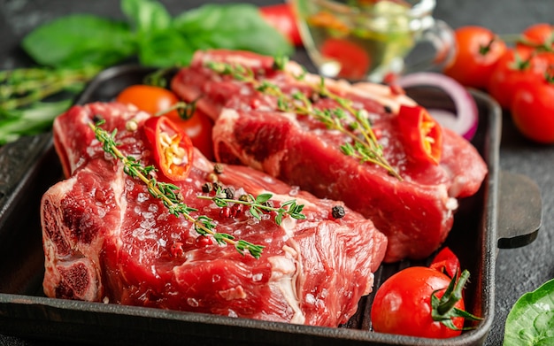 Raw red meat bone steaks on grill pan with spices and herbs