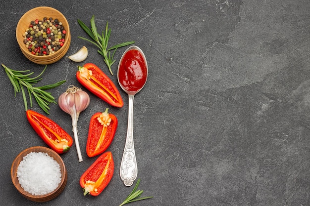 Raw red pepper, garlic and tomato sauce in spoonAllspice and salt in wooden bowls.  Copy space. Flat lay. Black background