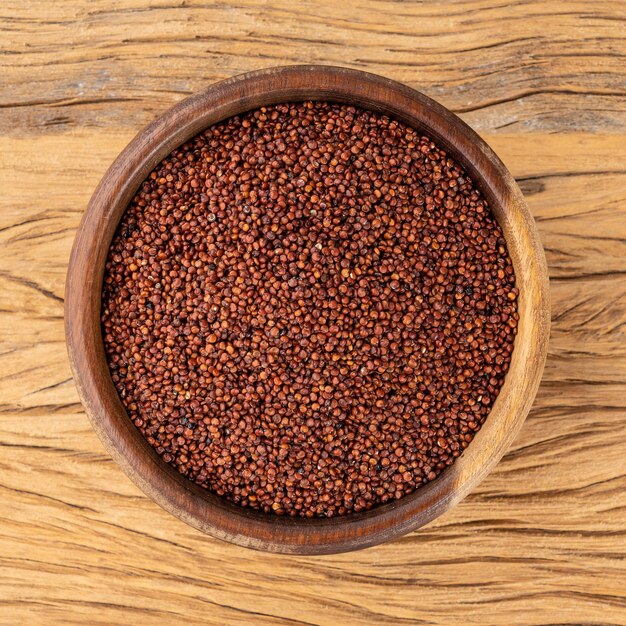 Raw red quinoa in a bowl over wooden table