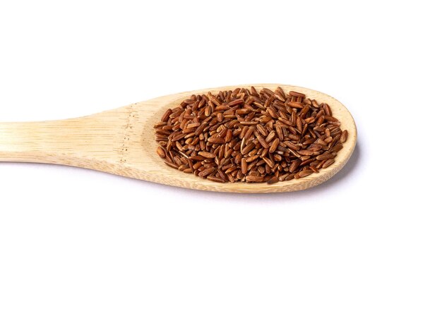 Raw red rice in a spoon isolated over white background