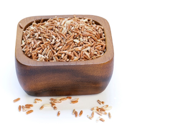 Raw red rice in a wooden cup isolated on white background.