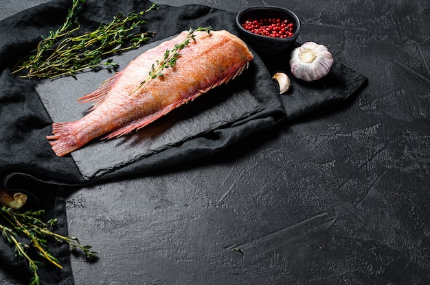 Raw red sea bass on a stone Board with thyme. Top view. Copyspace