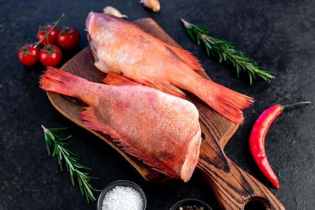 Raw red sea bass with rosemary and spices on stone background