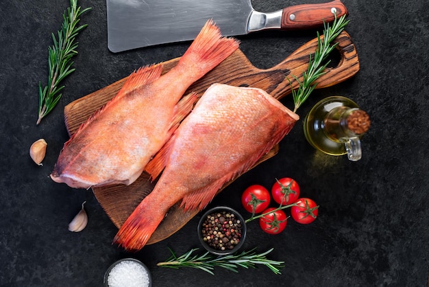 Raw red sea bass with rosemary and spices on stone background