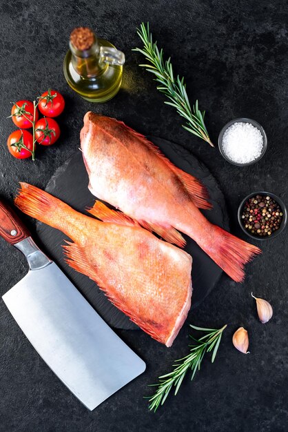 Raw red sea bass with rosemary and spices on stone background