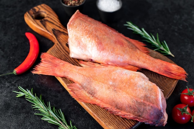 Raw red sea bass with rosemary and spices on stone background