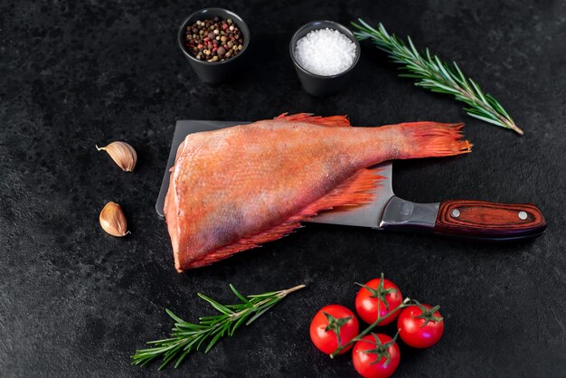 Raw red sea bass with rosemary and spices on stone background