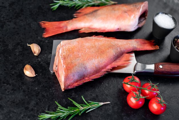 Raw red sea bass with rosemary and spices on stone background