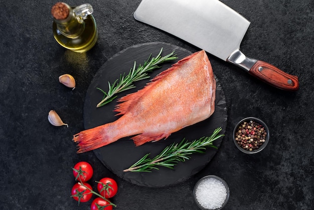 Raw red sea bass with rosemary and spices on stone background