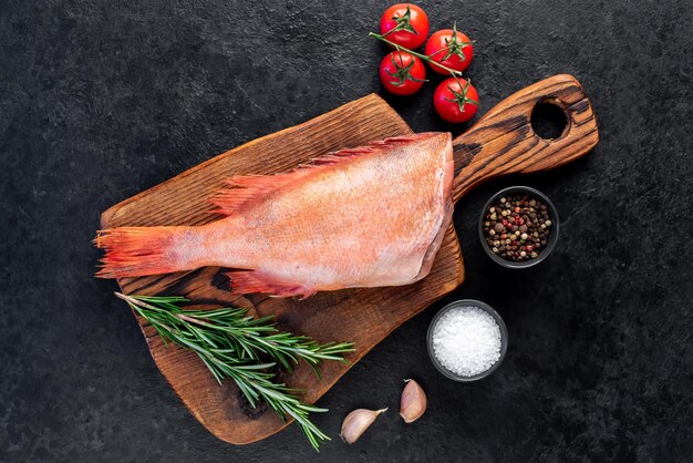 Raw red sea bass with rosemary and spices on stone background