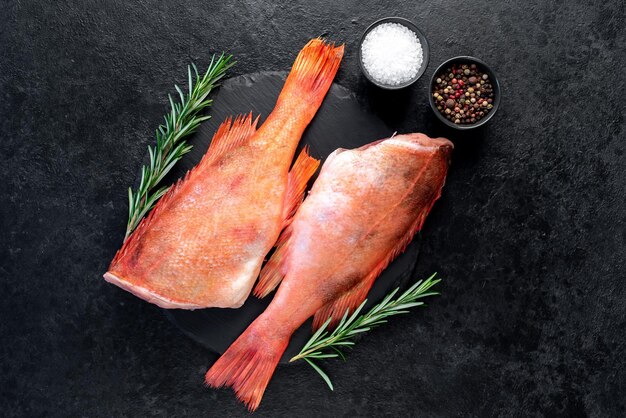 Raw red sea bass with rosemary and spices on stone background