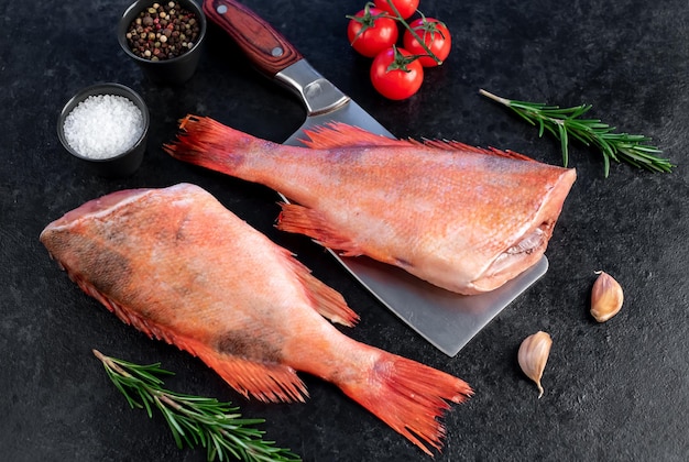 Raw red sea bass with rosemary and spices on stone background