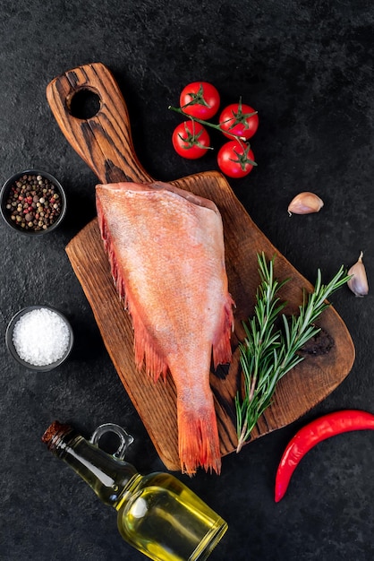 Raw red sea bass with rosemary and spices on stone background