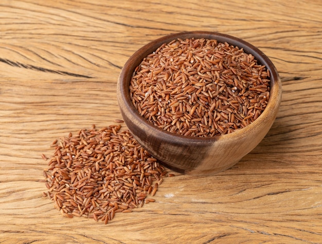 Raw red whole rice in a bowl over wooden table