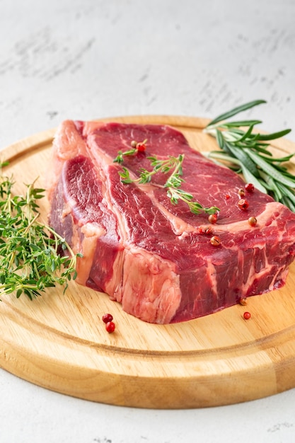 Raw rib eye beef steak with thyme and rosemary