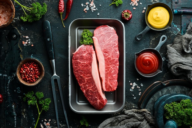 Raw rib eye steak of beef on a black stone background Top view Raw meat