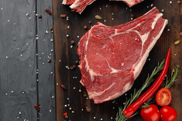 Raw rib eye steak on brown wooden board