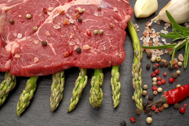 Raw rib eye steak with spices and vegetables