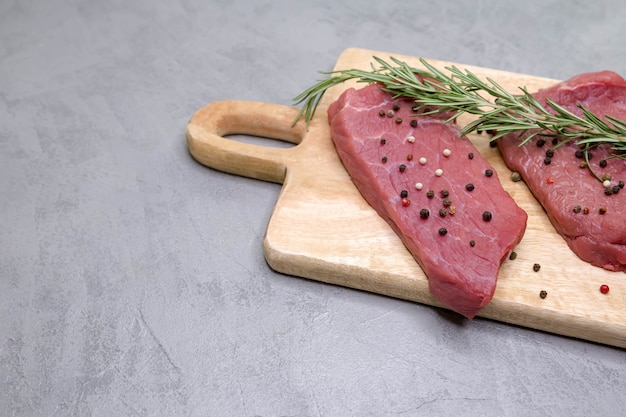 raw rib eye steak on wooden cutting board