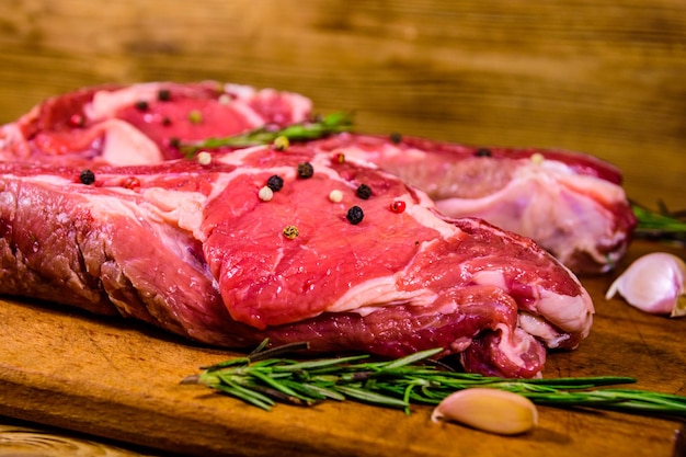 Raw ribeye steak spices rosemary and garlic on cutting board