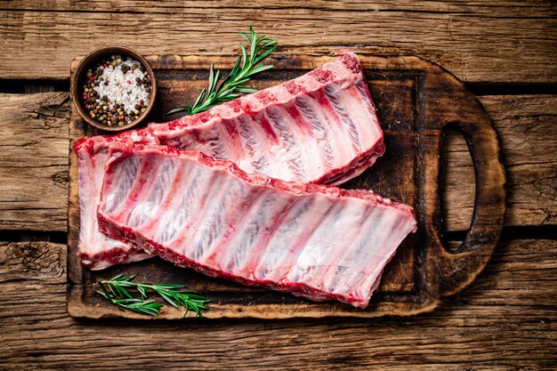 Raw ribs with spices and rosemary on a cutting board