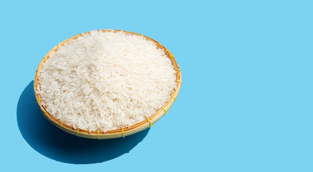 파란색 배경에 대나무 바구니에 생 쌀입니다.