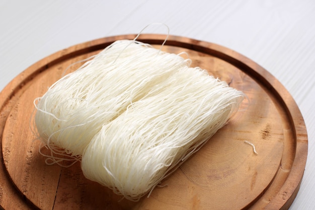 Фото Сырая рисовая лапша, сырая вермишель на кухне, готовая к приготовлению. изолированные на белом