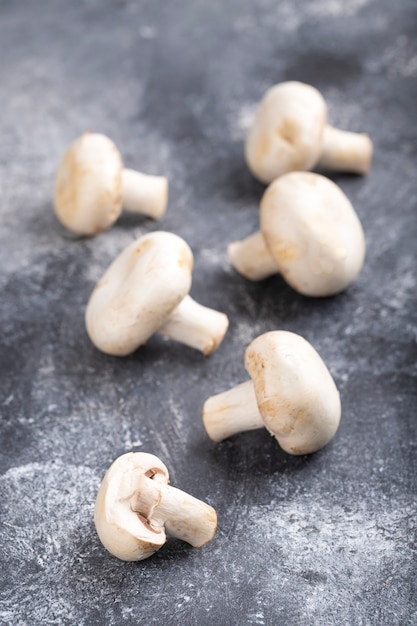 Raw ripe champignon mushrooms placed on marble table.