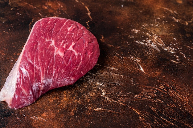 Raw rump beef cut or top sirloin meat steak on butcher table. dark background. top view. copy space