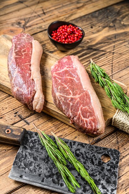 Raw rump cap steak on a chopping Board. Top view.