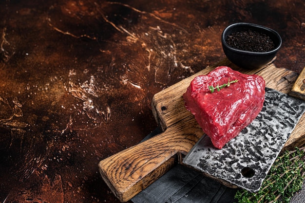 Raw rump steak on a butcher cutting board Dark background Top view Copy space