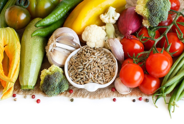 Raw Rye Grain in a bowl and vegetables isolated on white