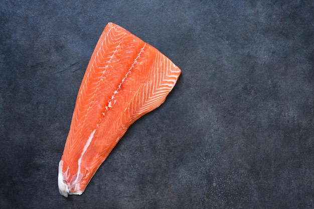 黒の背景に生のサーモンフィレ。平らに食べ物。