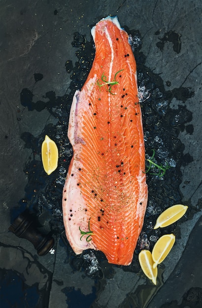 Raw salmon filet with lemon and rosemary on chipped ice