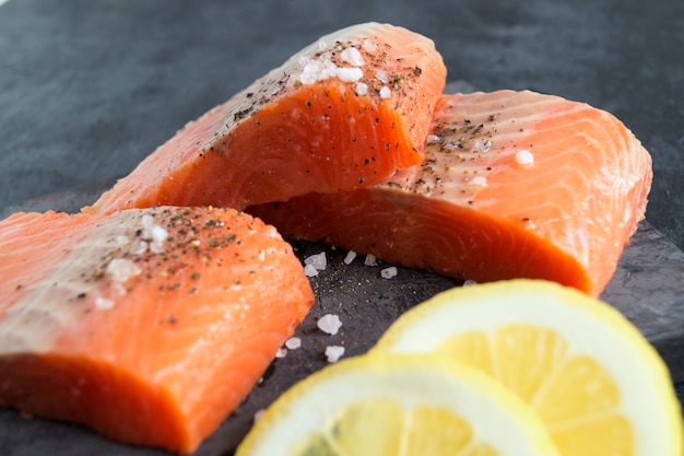 Raw salmon fillet and ingredients for cooking on a dark background in a rustic style. Top view