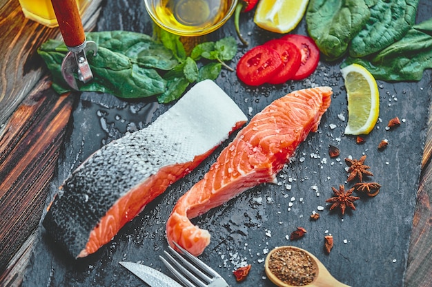 Raw salmon fillet and ingredients for cooking on a dark .