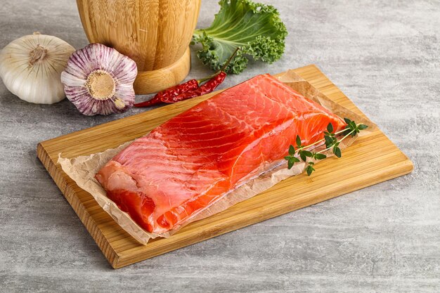 Raw salmon fillet piece over board