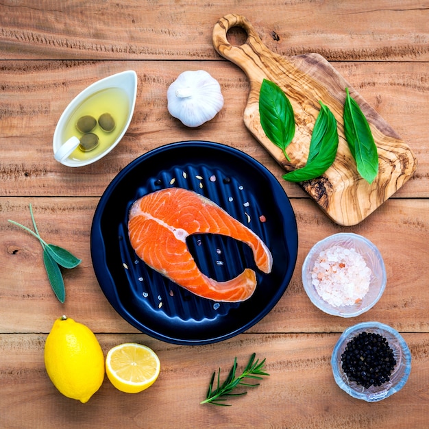 Raw salmon fillet with ingredients  on wooden background .