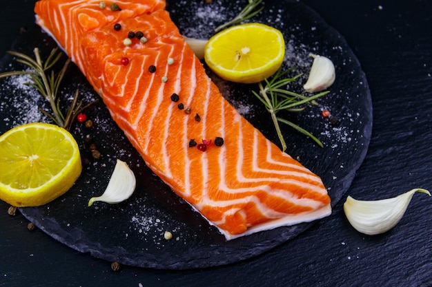 Raw salmon fillet with spices on black slate