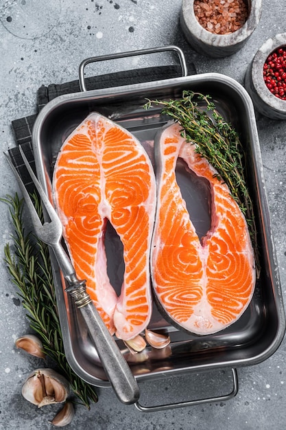 Raw Salmon Fish Steaks prepared for cooking with thyme and rosemary Gray background Top view