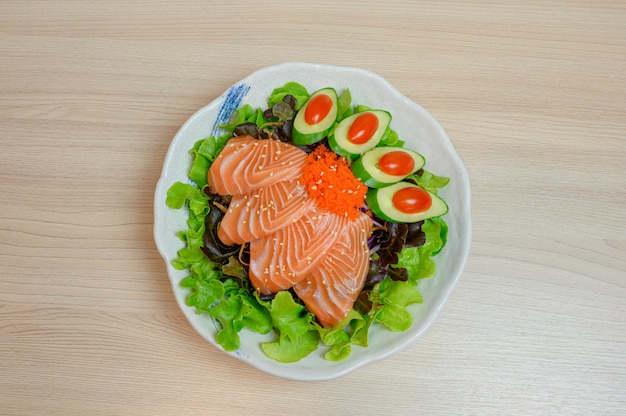 Сырые лосось сашими с овощами в керамической миске