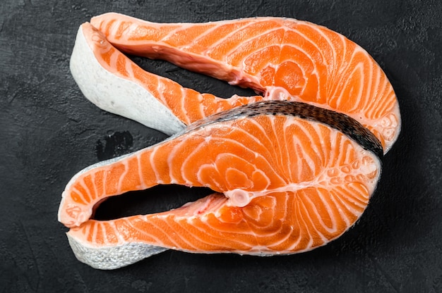 Raw salmon steak. Atlantic fish. Black background. Top view