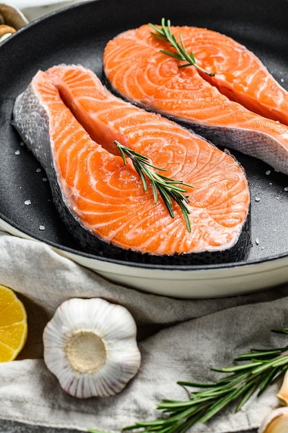 Raw salmon steak in a frying pan. Healthy seafood. Gray background. Top view