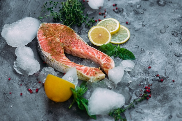 Foto trancio di salmone crudo con ghiaccio alle erbe e limone su sfondo grigio