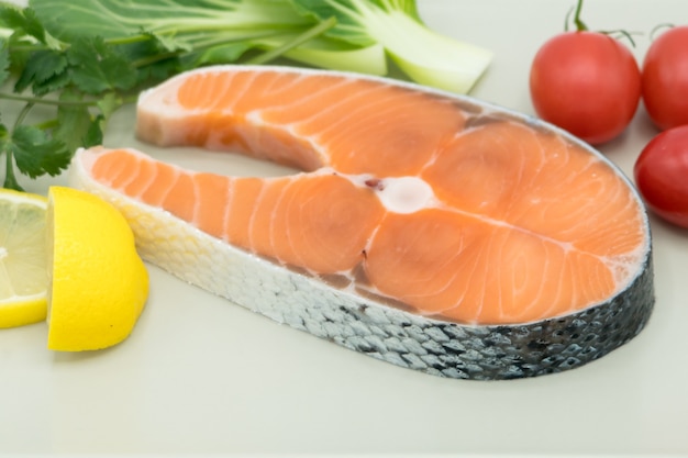 Стейк из сырого лосося с овощами на тарелке, концепция продуктов и овощей