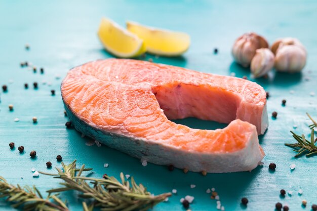 Raw salmon steak on wooden on blue surface