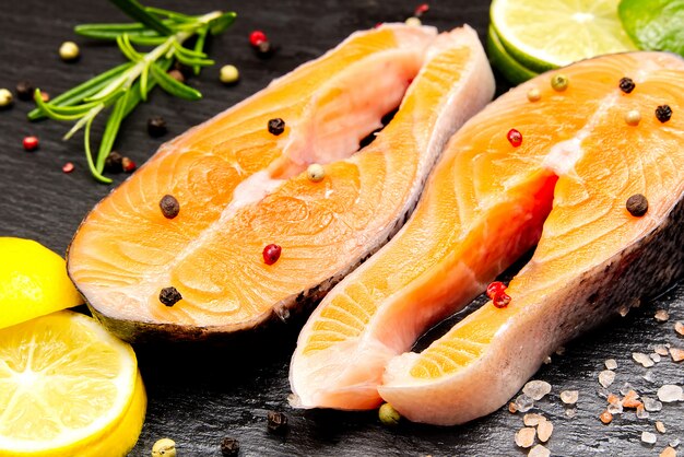 Raw salmon steak on wooden board with spices