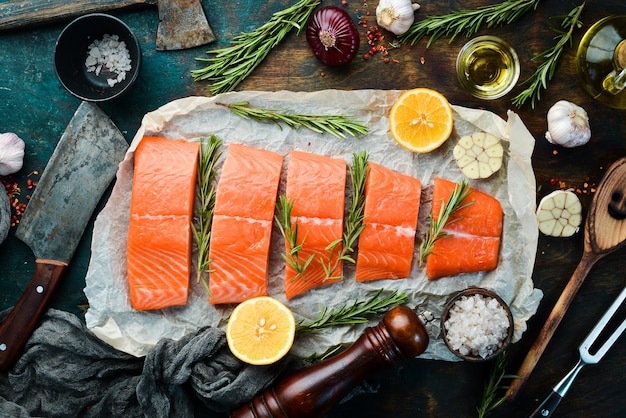 Raw salmon with rosemary lemon and vegetables on a black stone background Seafood Top view Free space for text