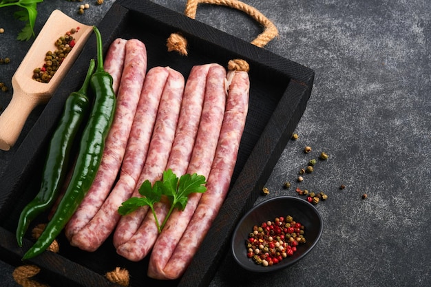 Raw sausages Bratwurst or sausages with ingredients on cutting board with spices on a stone background with copy space Food cooking background Top view