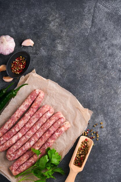 Raw sausages Bratwurst or sausages with ingredients on cutting board with spices on a stone background with copy space Food cooking background Top view